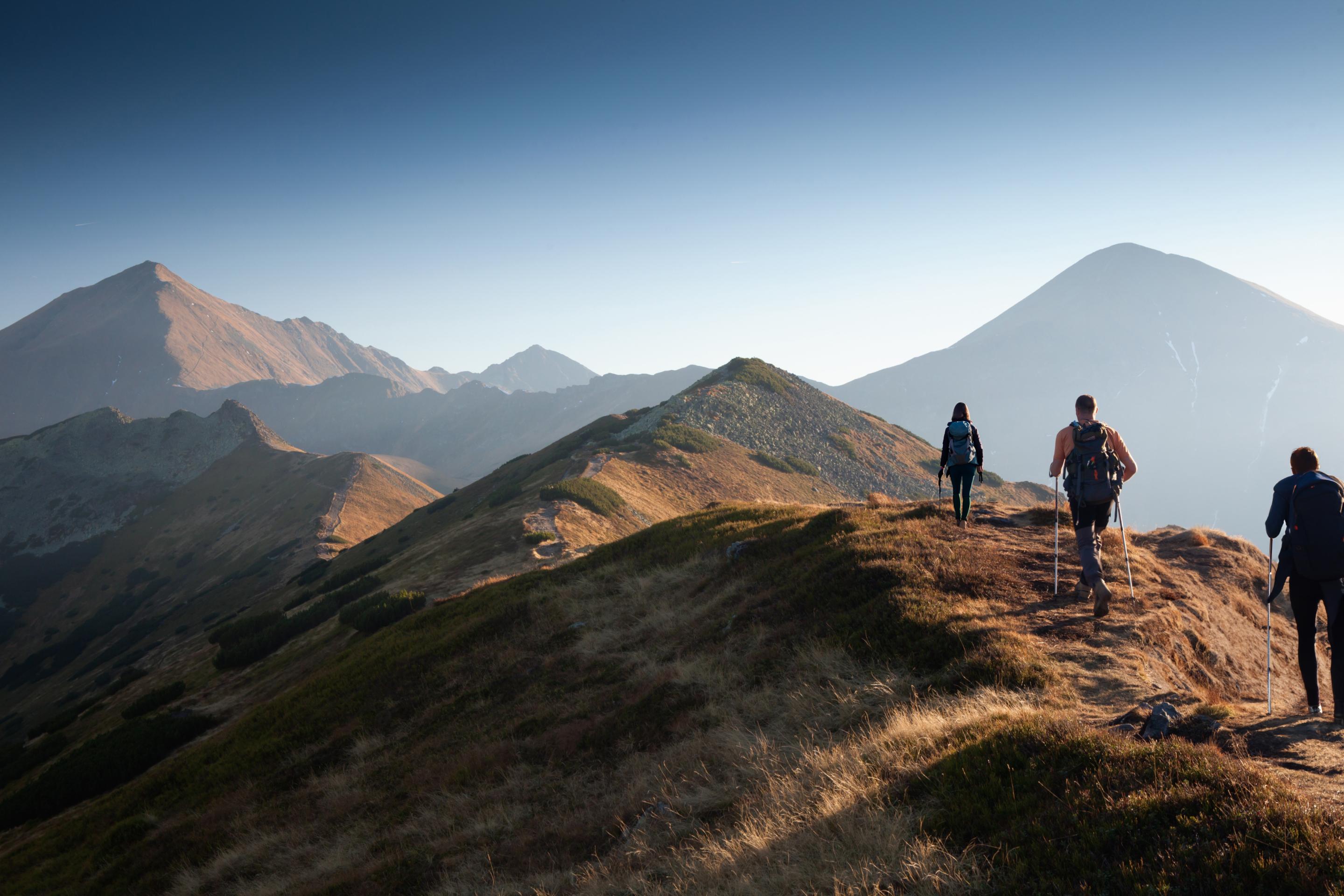 Persone che camminano in vetta ad una collina montuosa al tramonto